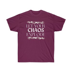 May include: A maroon t-shirt featuring the white text "LET YOUR CHAOS EXPLODE", framed by decorative white flame designs. The shirt has a crew neck and short sleeves.