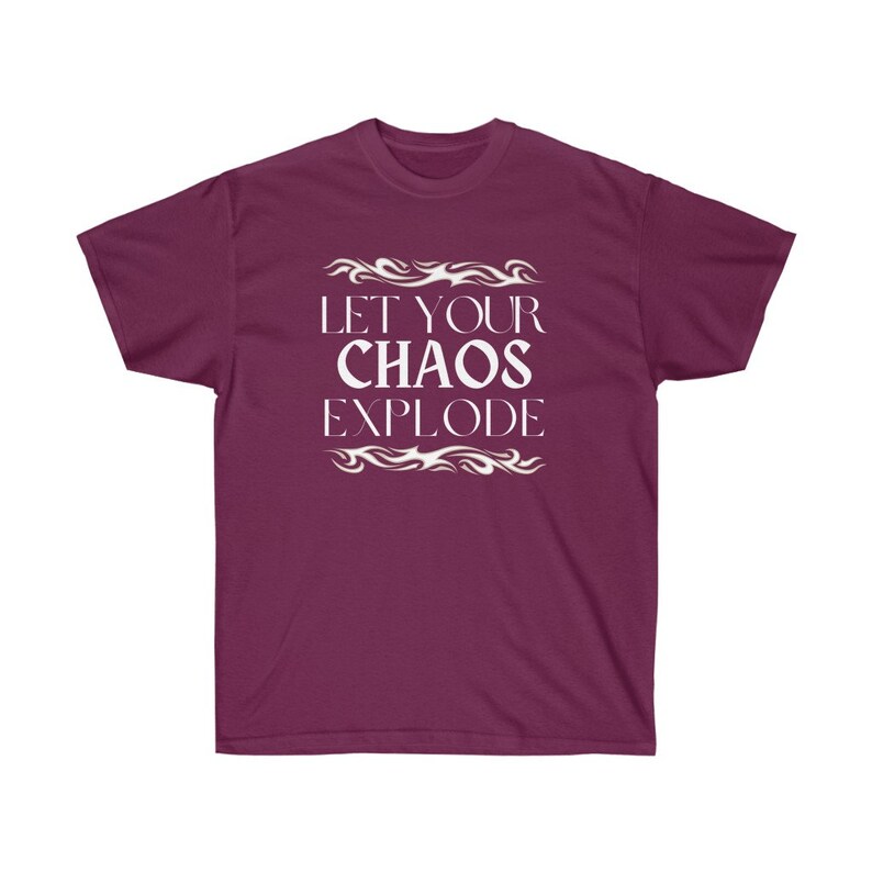 May include: A maroon t-shirt featuring the white text "LET YOUR CHAOS EXPLODE", framed by decorative white flame designs. The shirt has a crew neck and short sleeves.