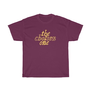May include: Burgundy t-shirt with the text "the chosen one" in yellow.