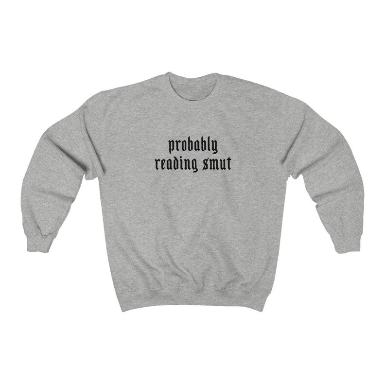 Puede incluir: Sudadera gris claro con la frase "probably reading smut" en fuente g&oacute;tica negra en el pecho. La sudadera tiene mangas largas y cuello redondo.