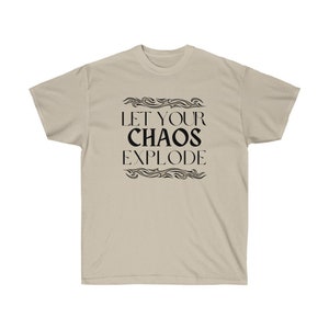 May include: A beige t-shirt featuring the black text "LET YOUR CHAOS EXPLODE", framed by decorative wavy lines. The shirt is made of a soft material. The design is centered on the front of the tee.