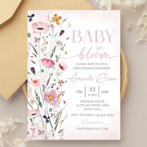 May include: Baby shower invitation with a watercolour floral design. The invitation reads "BABY in bloom" and includes details for Amanda Green's baby shower, including date, time, and location. The design features pink and purple flowers.