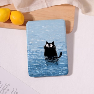 May include: A rectangular protective case featuring a graphic illustration of a black cat with wide eyes partially submerged in blue rippling water. The design covers the entire front surface of the case, showcasing a calm blue water texture.