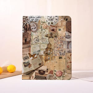 Op de afbeelding: Een decoratieve journal cover met een collage ontwerp. Het ontwerp bevat vintage elementen zoals een klok, bloemen, vlinders, een typemachine en architecturale illustraties.