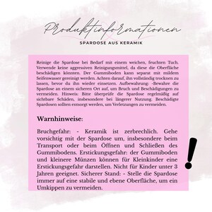 May include: A pink information sheet with black text about a ceramic piggy bank. The text includes cleaning instructions, storage advice, and warnings about breakage and choking hazards. An exclamation point is in the lower right corner.