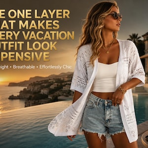 May include: A woman wearing a white, open-front, short-sleeved cardigan with a geometric pattern. She is wearing a white top and denim shorts. The text on the image reads: "THE ONE LAYER THAT MAKES EVERY VACATION OUTFIT LOOK EXPENSIVE."