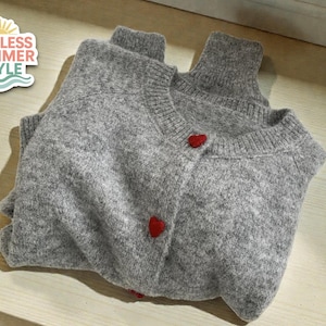 May include: A folded gray cardigan with a turtleneck collar and red heart-shaped buttons. The image includes the text "ENDLESS SUMMER STYLE" in a decorative logo.