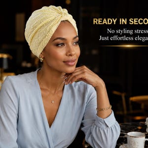 May include: A pale yellow lace turban featuring a knotted front detail. The text on the right side reads: READY IN SECONDS. No styling stress. Just effortless elegance. The head covering has a textured floral pattern throughout the fabric.