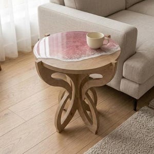 May include: A small, round wooden side table with a unique design. The tabletop features a pink and white resin design resembling ocean waves. A beige teacup sits on the table. The table is approximately 20 inches in diameter and 20 inches tall.