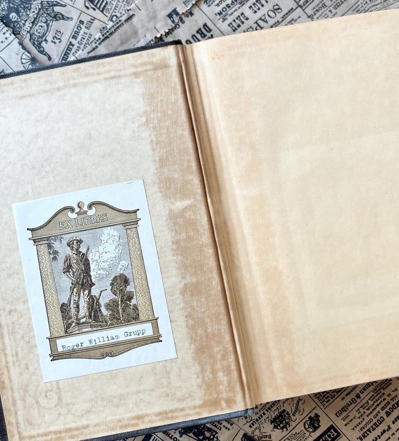 May include: A book with a brown leather cover and a bookplate that reads "Ex Libris Roger William Grupp". The bookplate features a black and white illustration of a man in a hat and coat holding a stick.