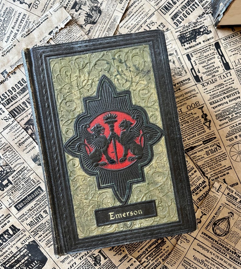 May include: A vintage hardback book with a dark green and gold cover. The cover features an embossed design with two mythical creatures holding a torch. The title "Emerson" is printed in gold lettering on the front cover.