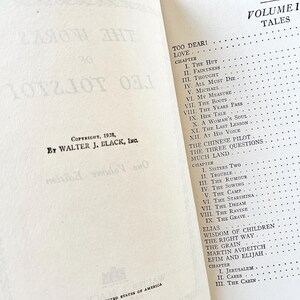 May include: A vintage book titled "Too Dear! Love" with a table of contents listing chapters for the book. The book is printed in black ink on white paper and has a copyright date of 1928.