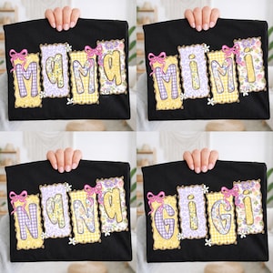 May include: Black t-shirts with the words "MAMA", "MIMI", "NANA", and "GIGI" in a decorative font. Each word is in a different pattern, including gingham, floral, and solid colors, with pink bow accents.