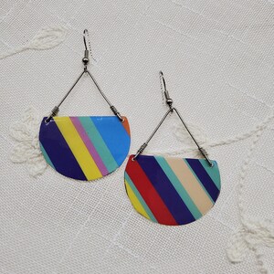 May include: A pair of colorful striped earrings with silver wire hangers. The earrings are half-circle shaped and feature a variety of colors, including red, yellow, blue, green, and purple.