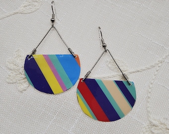 May include: A pair of colorful striped earrings with silver wire hangers. The earrings are half-circle shaped and feature a variety of colors, including red, yellow, blue, green, and purple.