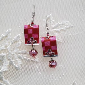 May include: A pair of pink and white checkered earrings with silver accents and pink crystal drops.