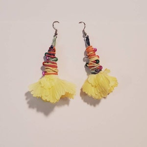 May include: A pair of yellow flower-shaped earrings with colourful string and beads hanging from silver hooks.