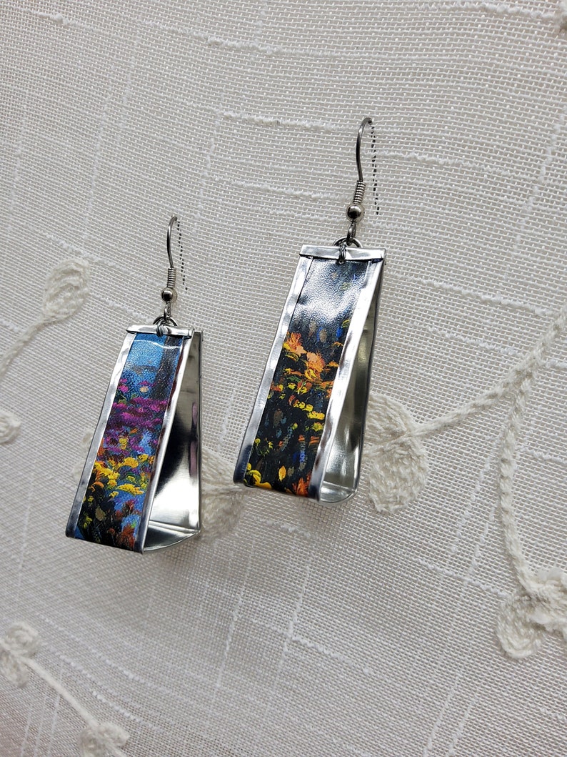 May include: A pair of silver earrings with a rectangular shape. The earrings are decorated with colorful abstract floral patterns.