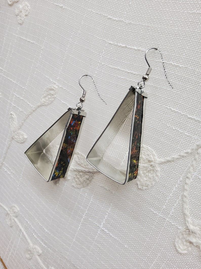 May include: A pair of silver triangle earrings with a colorful abstract design on the inside of the triangle.