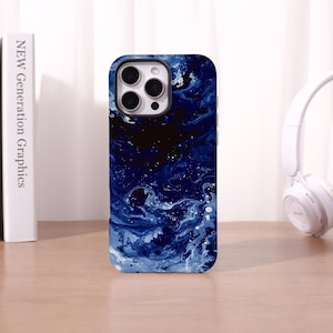 May include: A smartphone case with a dark blue, swirling, abstract design. The case has a glossy finish and features a camera cutout. The case is on a wooden surface next to a book and a pair of white headphones.