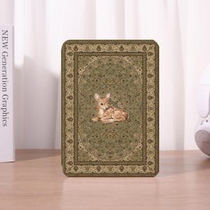 May include: A rectangular case featuring a detailed, olive green rug design with a central image of a fawn. The case has a decorative border and the text "NEW Generation Graphics" is visible on the left.