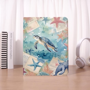 Può includere: Una custodia rettangolare per tablet con un'illustrazione ad acquerello di una tartaruga marina che nuota tra acqua blu, coralli, stelle marine e frammenti di carta in stile vintage. Il design presenta tonalità blu ottanio, marino e corallo.