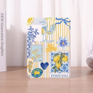 Könnte beinhalten: Ein dekorativer rechteckiger Gegenstand mit einer Collage von Aquarellillustrationen. Das Design umfasst Zitronen, Blumen und Cocktailgläser, mit Text, der "Italy", "Ottolenghi Test Kitchen" und "Positano" lautet. Der Hintergrund hat gelbe und weiße Streifen.