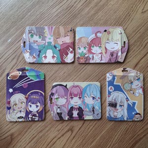 May include: Six colourful cardholders featuring anime-style illustrations of various characters. The cardholders display different designs, including groups of characters and space-themed graphics. Each cardholder has a unique colour scheme and character arrangement.