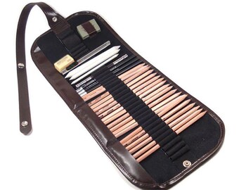 May include: A brown leather pencil roll case, open to display a variety of drawing pencils, erasers, and blending stumps. The case is black inside with individual slots for each pencil. A brown strap is attached for carrying.