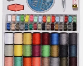 May include: A sewing kit with various tools and supplies. The kit includes spools of thread in multiple colors, needles, scissors, a tape measure, and other sewing accessories. The items are neatly arranged in a white box, ideal for sewing projects.