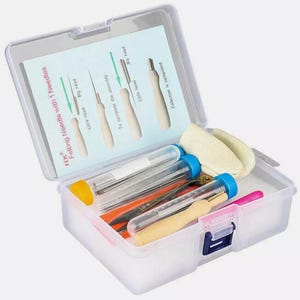 May include: A clear plastic craft kit containing felting needles, tools, and accessories. The kit includes needles, tubes, and a small felt pad. The lid has instructions for needle felting. The kit is designed for crafting and DIY projects.