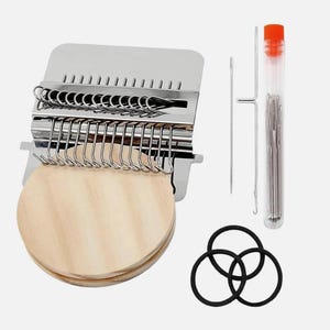 May include: A metal darning loom tool with a round wooden base, featuring a series of silver hooks. Included are two long metal needles, a clear plastic tube containing multiple sewing needles, and three black rubber bands for securing fabric.