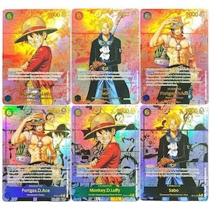 Peut inclure: Six cartes à collectionner One Piece avec des personnages tels que Monkey D. Luffy, Sabo et Portgas D. Ace. Les cartes présentent des illustrations, des fonds holographiques et du texte japonais. Chaque carte a une valeur numérique.
