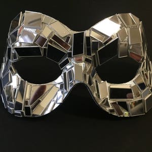 May include: A silver masquerade mask made of small mirrored tiles. The mask has a unique geometric design and is perfect for a costume party or a night out.