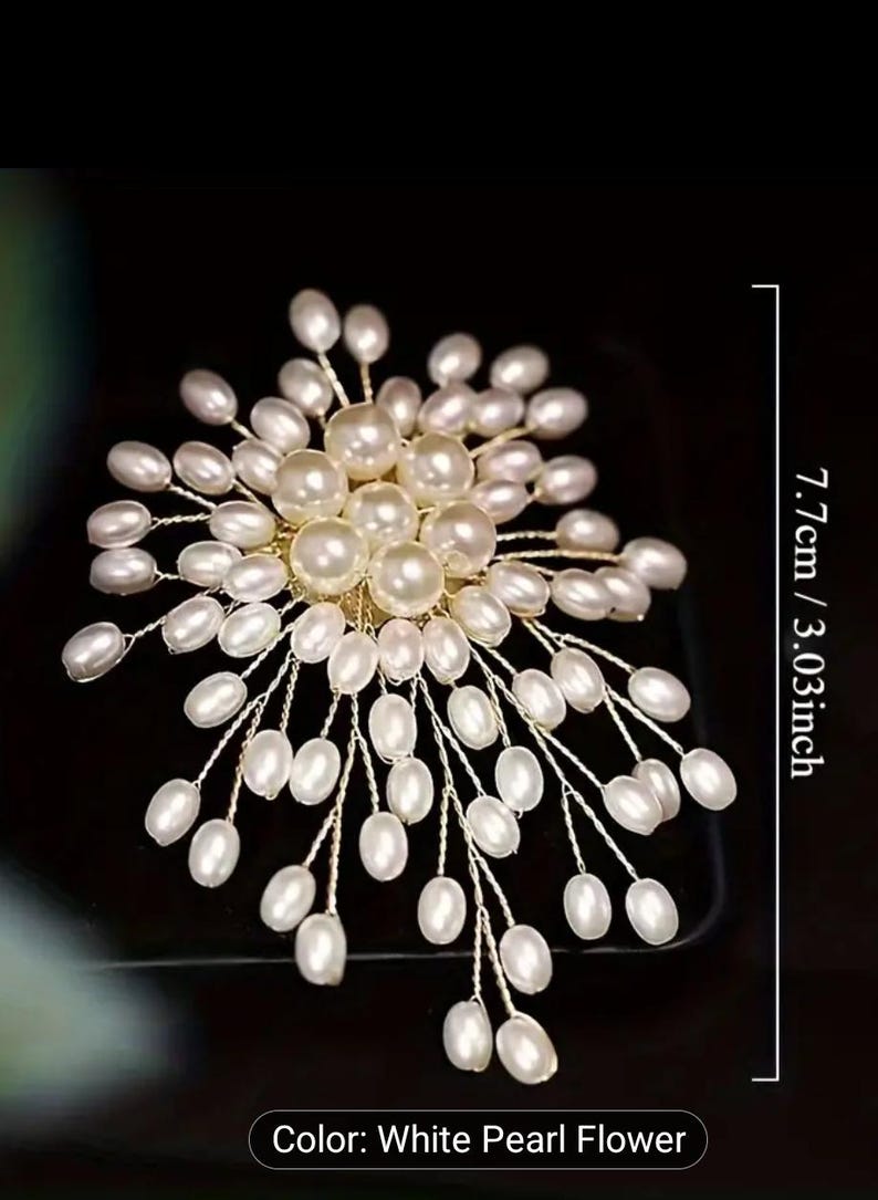 Puede incluir: Accesorio para el cabello con forma de flor de perlas blancas, de aproximadamente 7,7 cm de largo. El dise&ntilde;o presenta numerosas perlas blancas agrupadas en delicados tallos de alambre dorado, creando un arreglo floral. El fondo es negro.