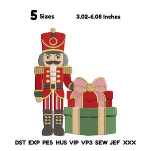 May include: An embroidery design of a nutcracker in a red uniform with gold accents, standing next to a stack of two wrapped gifts with a large pink bow. The text reads 5 Sizes, 3.02-6.08 Inches, and file formats DST, EXP, PES, HUS, VIP, VP3, SEW, JEF, XXX.