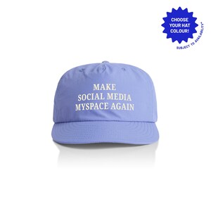Puede incluir: Gorra de béisbol de color lila claro con el texto "MAKE SOCIAL MEDIA MYSPACE AGAIN" en blanco. La gorra tiene una visera curva y una corona redondeada. Un gráfico azul en forma de estrella en la esquina superior derecha dice "CHOOSE YOUR HAT COLOUR!"