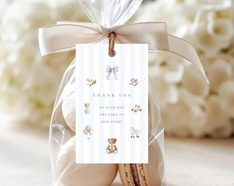 May include: A clear cellophane bag tied with a cream ribbon, containing macarons. A tag with blue stripes and baby-themed illustrations reads "THANK YOU, SO GLAD YOU ARE PART OF OUR STORY."