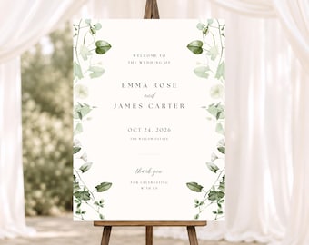 May include: A rectangular wedding welcome sign on a wooden easel featuring a white background with green watercolor botanical illustrations of vines and leaves along the sides. The text reads: Welcome to the wedding of Emma Rose and James Carter, Oct 24, 2026, The Willow Estate, thank you for celebrating with us.