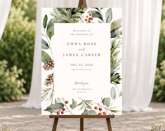 May include: A rectangular wedding welcome sign on a wooden easel featuring watercolor greenery, pinecones, and red berries. The text reads: WELCOME TO THE WEDDING OF EMMA ROSE and JAMES CARTER DEC 12, 2026 THE WILLOW ESTATE thank you FOR CELEBRATING WITH US.