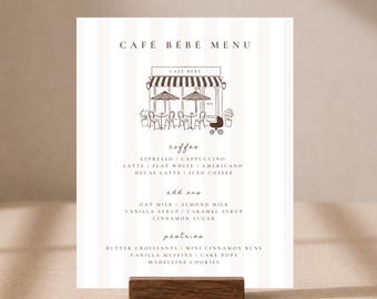 May include: A vertical menu card titled CAFÉ BÉBÉ MENU with a white and light gray striped background. It features a brown line drawing of a cafe storefront with tables, chairs, and a baby carriage. The text lists coffee, add-ons, and pastries.