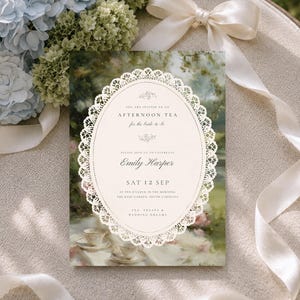 May include: A rectangular invitation card featuring an oval center with a white lace border. The text reads: You are invited to an afternoon tea for the bride-to-be, please join us to celebrate Emily Harper, Sat 12 Sep, at ten o'clock in the morning.