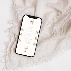 May include: A smartphone displays a gender reveal invitation. The invitation features watercolor illustrations of toys and a hot air balloon. The text reads "Gender Reveal" and includes the names Daisy & Theo and the date, Sun 22 Feb.