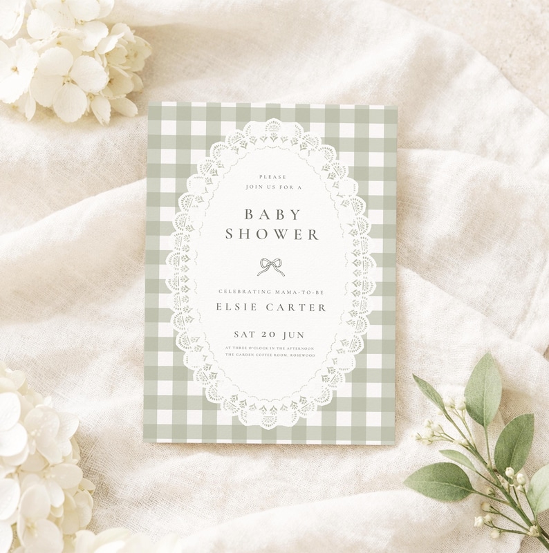 Puede incluir: Una invitaci&oacute;n para un baby shower con un fondo de patr&oacute;n de cuadros vichy en tonos verdes y blancos. La invitaci&oacute;n presenta un marco ovalado de encaje con las palabras "Baby Shower" y el nombre "Elsie Carter".