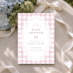 May include: A rectangular baby shower invitation card featuring a light pink and white gingham pattern. The center displays a white oval frame with a delicate lace border, containing the text: PLEASE JOIN US FOR A BABY SHOWER, ELSIE CARTER.