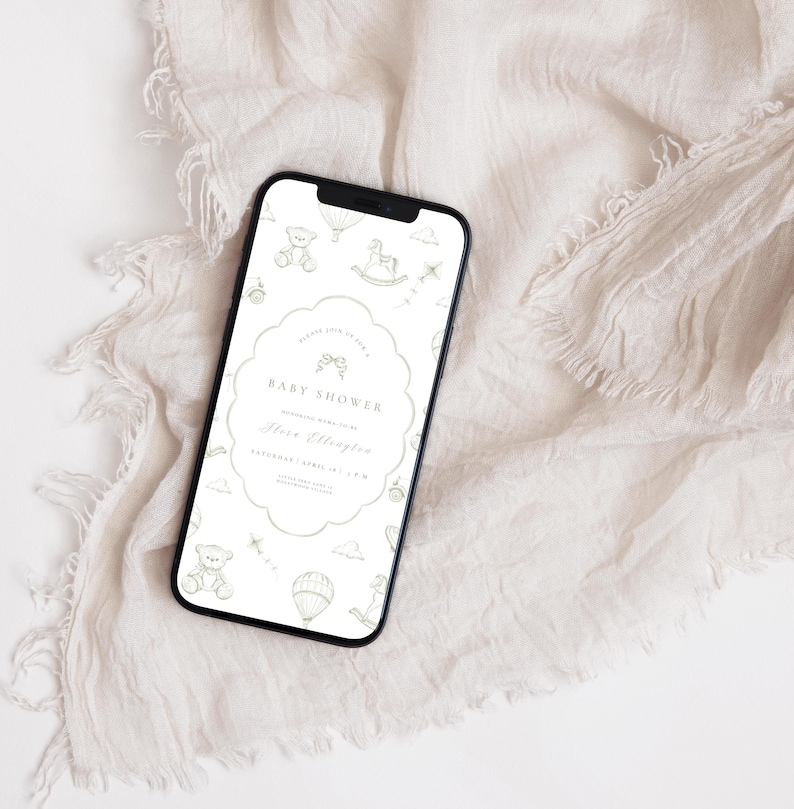 May include: A smartphone screen shows a baby shower invitation. The invitation has a scalloped edge and includes text with the words "Baby Shower" and event details. The background is a soft, neutral colour with baby-themed illustrations.