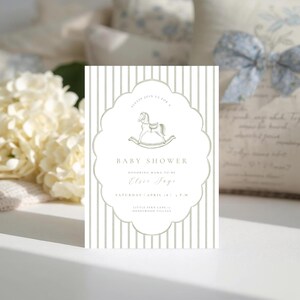 May include: A baby shower invitation with a rocking horse illustration. The invitation has a scalloped border and vertical stripes in a soft green and white colour scheme. The text reads "Baby Shower" and the name "Elsie Foye".