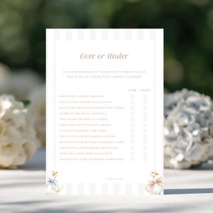 May include: A baby shower game card with the text "Over or Under" in a script font. The card has a striped background and features a list of questions with spaces to check "Over" or "Under". Two cartoon geese with bows are at the bottom.