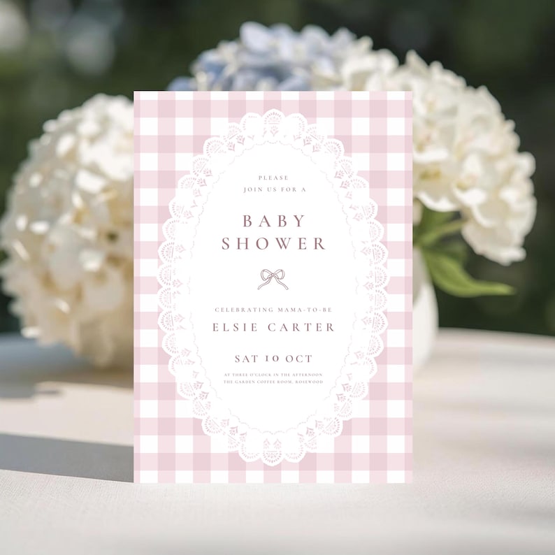 May include: A rectangular baby shower invitation card featuring a light pink and white gingham pattern. The center displays a white oval frame with a delicate lace border, containing text that reads: PLEASE JOIN US FOR A BABY SHOWER, ELSIE CARTER.