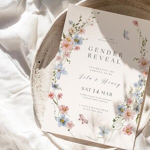 May include: A rectangular gender reveal invitation card featuring watercolor illustrations of pink and blue wildflowers and two small butterflies. The text reads: You are invited to a Gender Reveal, celebrating the parents to be, Zila & Henry, Sat 14 Mar, at three o'clock in the afternoon, 72 Willow Street, Fernville, a little wildflower is on the way.